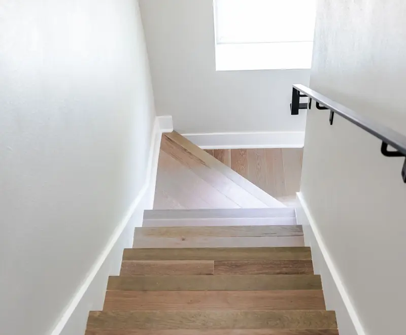 Oak staircase with white walls and a wall-mounted handrail